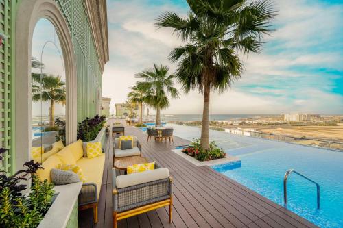多哈The Plaza Doha, LXR Hotels & Resorts的一个带游泳池和棕榈树的度假阳台