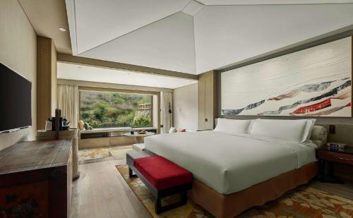 九寨沟九寨康莱德酒店的一间卧室设有一张大床和一个大窗户