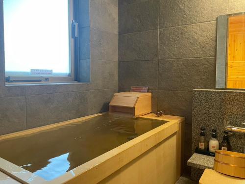 札幌Hatagoya Jozankei Shoten-Adult Only的浴室设有装满水的浴缸。