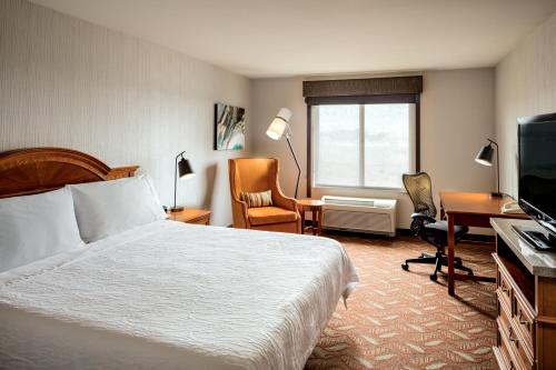 肯纳威克三城/肯纳威克希尔顿花园酒店的酒店客房配有一张床、一张书桌和一台电视。