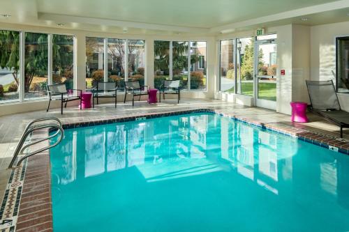 肯纳威克三城/肯纳威克希尔顿花园酒店的一个带蓝色水和椅子的游泳池以及窗户
