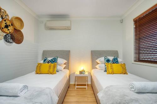 黄金海岸'Buzzing Surfers' Vibrant Indoor-outdoor Lifestyle的两张带黄色和蓝色枕头的床