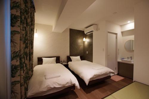 东京MARUKOU HOTEL的小客房内的两张床,配有白色床单