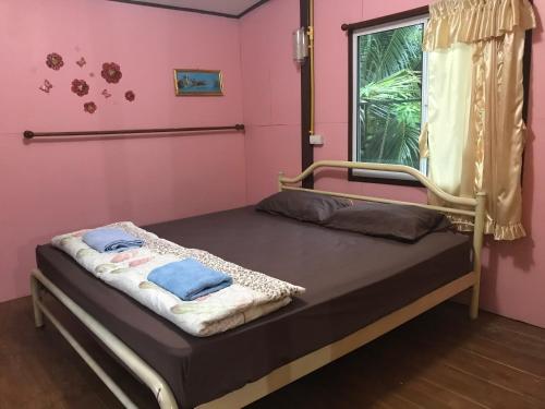 安帕瓦บ้านปุณยาพร โฮมสเตย์的粉红色墙壁的房间里一张床位