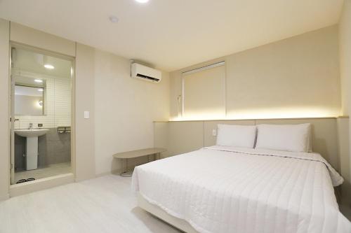 春川Chuncheon Pine Tree Hotel的卧室配有白色大床和水槽