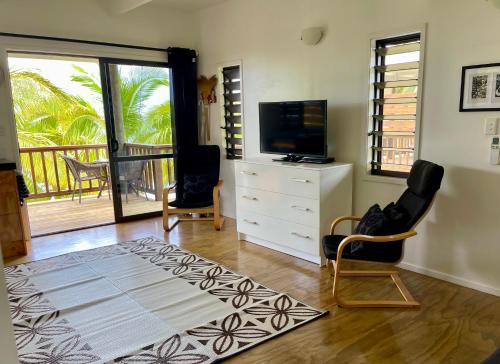 阿罗朗吉Rarotonga Villas Absolute Beachfront的客厅配有电视、梳妆台和椅子