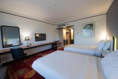 山打根沙巴大酒店的酒店客房设有两张床和电视。