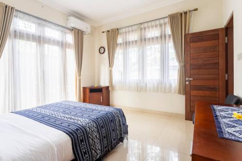 登巴萨Jenna Residence Denpasar的卧室配有一张床、一张书桌和窗户。