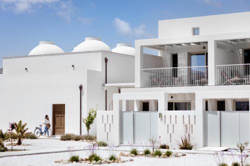 斯基罗斯岛ALERÓ Seaside Skyros Resort的一位在白色建筑前骑着自行车的女人