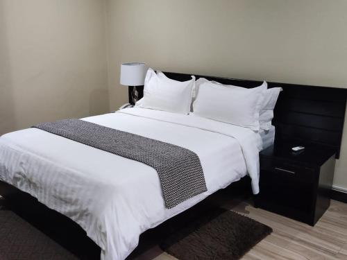 利隆圭Legacy Suites的卧室配有一张带白色床单和枕头的大床。