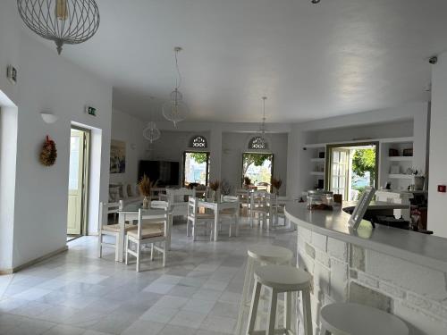 安迪帕罗斯岛阿特米斯酒店的一间设有白色椅子和酒吧的用餐室