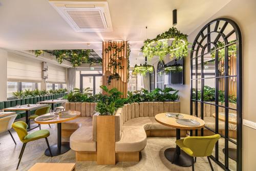 古拉哈莫卢洛伊Hotel DUKAT的一间设有桌椅的餐厅,种植了植物