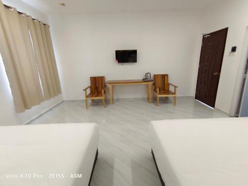 瓜拉丁加奴ASM Roomstay-4-2 Queen Beds的配有桌子和两把椅子以及电视的房间