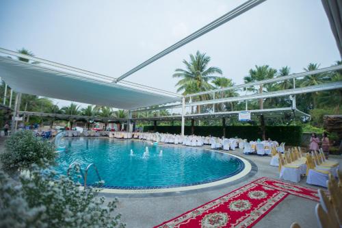 Ban Nam Mongโรงแรมแสงทองรีสอร์ท的一个带白色椅子的游泳池和一个泳池景