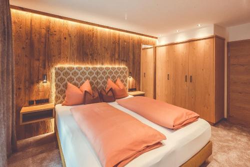 上施陶芬Hotel Alpenkönig的一间卧室配有一张带橙色枕头的大床