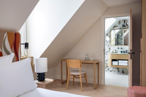 巴黎Padam Hôtel的卧室配有1张床、1张桌子和1把椅子