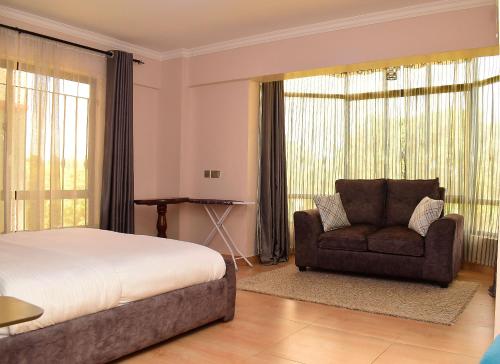 纳库鲁RAVIC HOMES NAKURU的一间卧室配有一张床、一张沙发和一把椅子