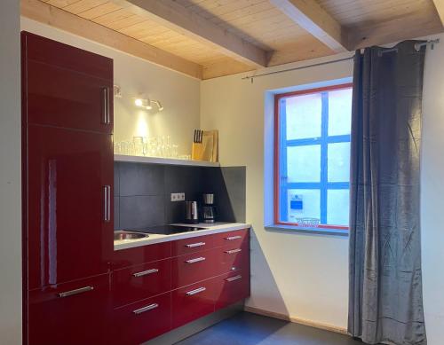 奎德林堡天堂&地狱自助式公寓酒店的一间厨房,配有红色橱柜和窗户