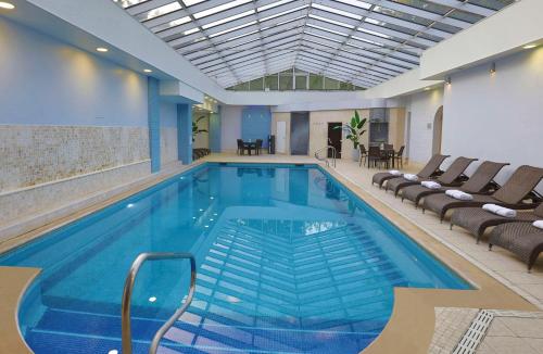泰姆DoubleTree by Hilton Oxford Belfry的一个带椅子和桌子的大型游泳池