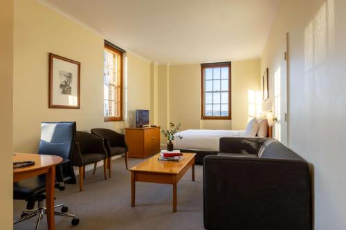 悉尼Sydney Harbour Hotel的酒店客房配有一张床、一张沙发和椅子。