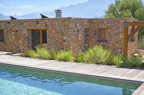 卡尔维Villa Bergeries De Calvi的一座石头房子,设有木路,毗邻一个游泳池