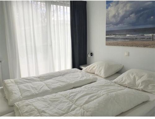 皮滕Knus chalet Heidebloem的卧室设有两张床和大窗户