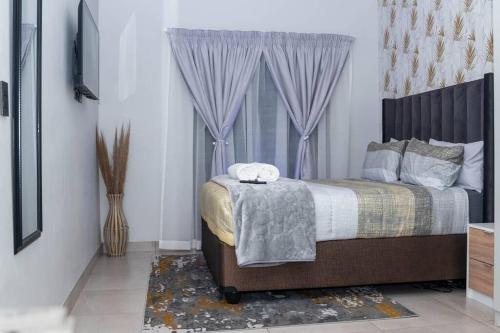 比勒陀利亚Apartments at Brooklyn/Waterkloof的一间卧室配有一张带紫色窗帘的床和窗户。