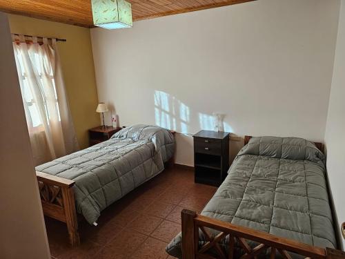 乌斯怀亚La Herradura de Ushuaia的一间卧室设有两张床、一张桌子和一个窗口。