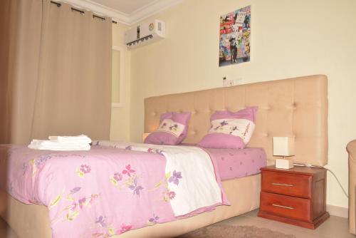 杜阿拉Polgaro duplex luxueux的一间卧室配有一张带粉色和白色床单及枕头的床。