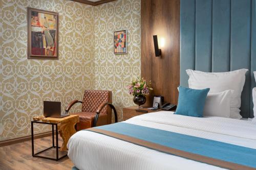 利雅德Madareem Hotel的酒店客房配有一张床、一张书桌和一台笔记本电脑