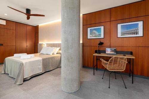 瓦伦西亚Calatrava by Alma Suites的一间卧室配有一张床和一张带笔记本电脑的书桌