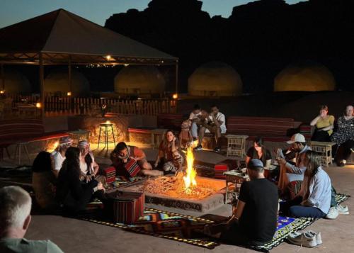 瓦迪拉姆Wadi Rum living camp的一群人坐在火坑周围