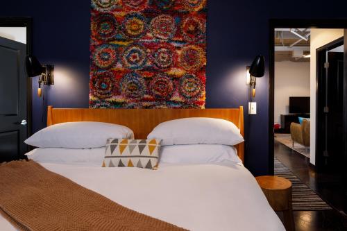 查塔努加Hotel Clemons的卧室配有一张白色大床,墙上挂着挂毯