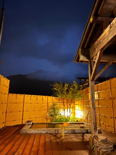 由布市湯布院 旅館 やまなみ Ryokan YAMANAMI的木质甲板,晚上设有木栅栏