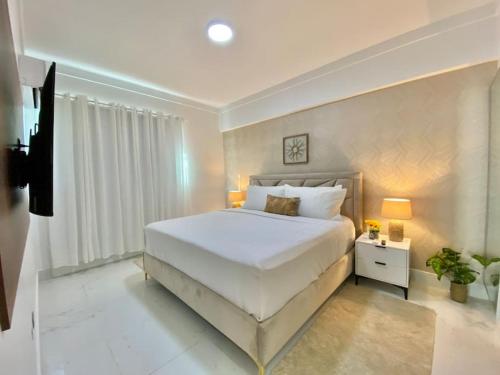 Los PradosUpscale City Center Condo的卧室设有一张白色大床和一扇窗户。