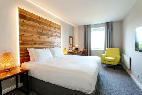 布雷得佛Cedar Court Bradford Hotel的酒店客房设有一张大床和一张黄色椅子