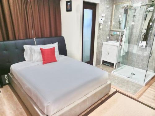 Brighton VillageMyah's Hotel的一间卧室配有一张带红色枕头和淋浴的床