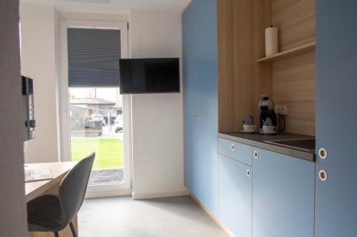 梅肯博伊伦MIWO的厨房配有蓝色橱柜、桌子和窗户。