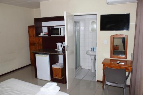 比勒陀利亚紫橄榄宾馆的客房设有一张床和一张带微波炉的书桌