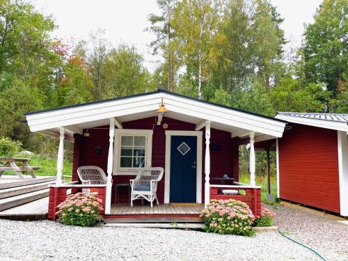 AsphyttanHöga Backe Gästhus的红色小屋,设有蓝色的门和椅子
