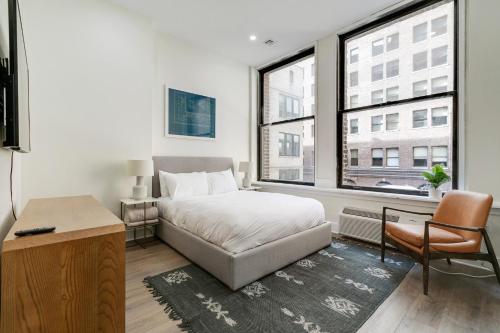 费城The Ledger Residences by Sosuite - Old City的一间卧室配有一张床、一张书桌和一个窗户。