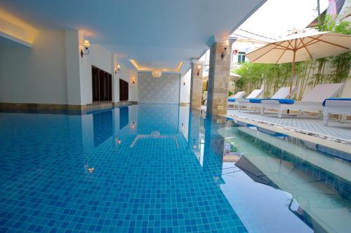 会安Lantana Boutique Hoi An Hotel的一个带椅子和遮阳伞的游泳池