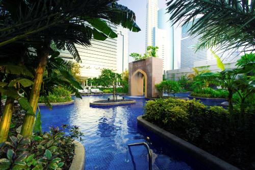 迪拜迪拜康莱德酒店的棕榈树和建筑度假村内的游泳池