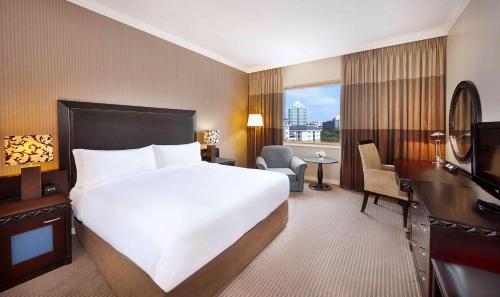 约翰内斯堡桑顿希尔顿酒店的酒店客房设有一张大床和一张书桌。