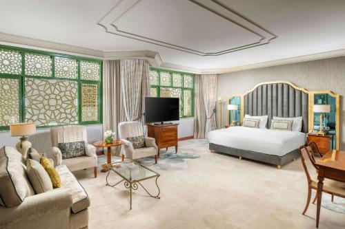 麦地那麦地那希尔顿酒店 的一间卧室配有一张床、一张沙发和一台电视。