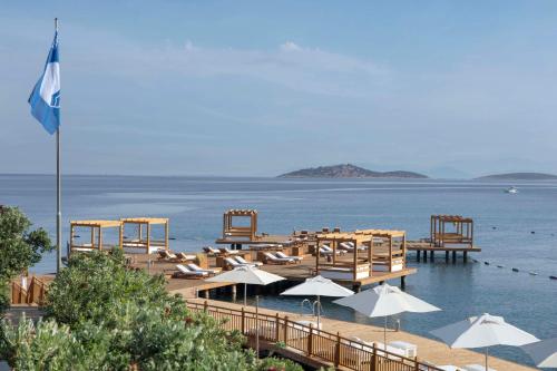 博德鲁姆Susona Bodrum, LXR Hotels & Resorts的海滩上摆放着椅子和遮阳伞