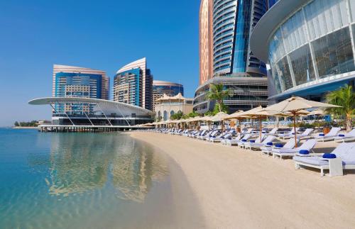阿布扎比Conrad Abu Dhabi Etihad Towers的建筑前的海滩,配有椅子和遮阳伞