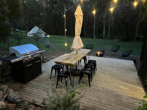 AlonnahBase Glamp Bruny - Heated Tents for 8 People的木制甲板上设有烧烤架和桌椅