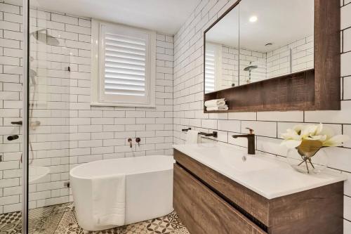 悉尼Sydney CBD Waterview apartment56的带浴缸、水槽和镜子的浴室