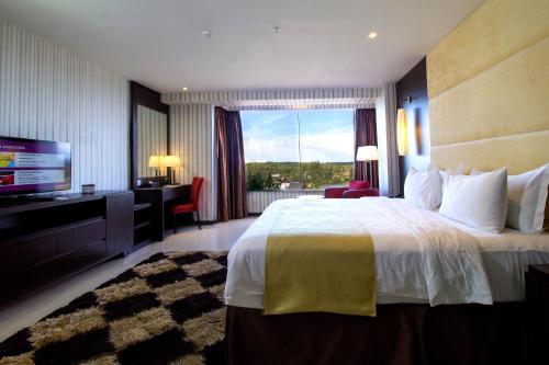 拉古洼Grand Lagoi Hotel Bintan的酒店客房设有一张大床和一台电视。